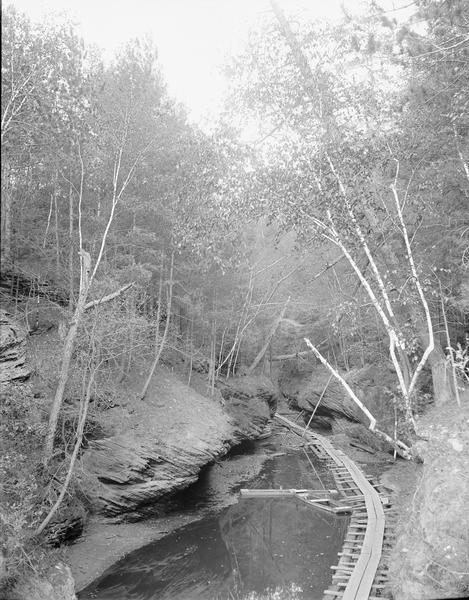 Elevated view of the entrance to Cold Water Canyon. There is a wooden walkway across the water.