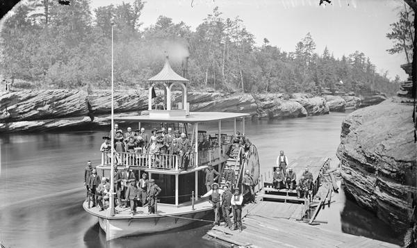 View from shoreline looking down at passengers posing on steamboat "Eolah" and on landing at shoreline.