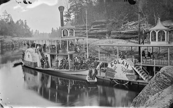 Steamboats <i>Alexander Mitchell</i> and <i>Eolah</i> alongside rocks, with passengers posed on the <i>Alexander Mitchell.</i>