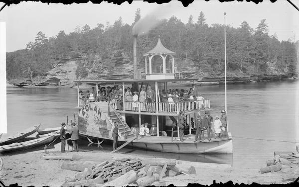 View looking down at passengers posing on the steamboat "Eolah" on the Wisconsin River shoreline.