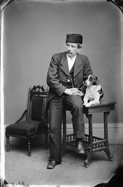 Studio portrait of H.H. Bennett and a dog.