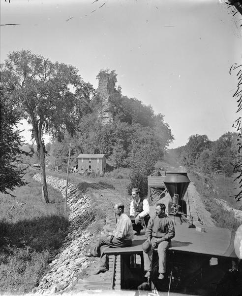 Upper Mississippi; Turkey River Bluff. Elevated view of three men sitting on top of a train engine at a junction.
