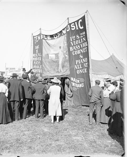 A crowd is standing in front of a tent advertised as the "Temple of Music."