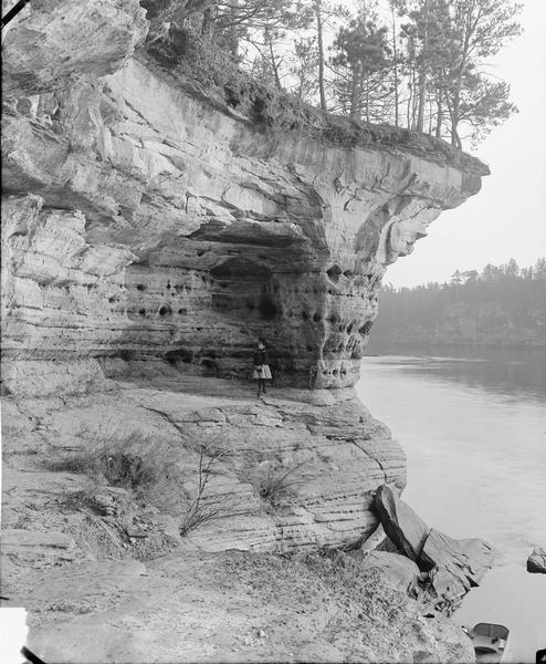 View along rock formation at the shoreline towards a girl standing on the north face of Swallows Nests.