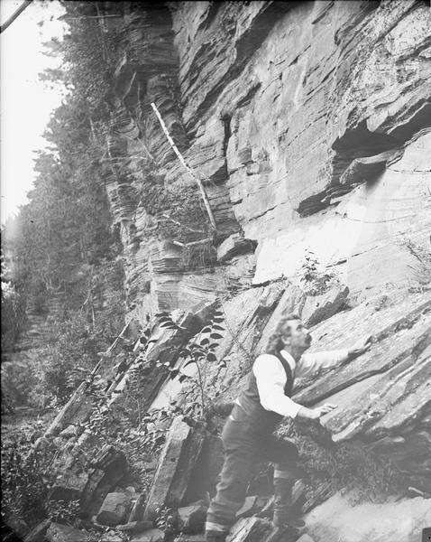 View of H.H. Bennett climbing rocks at Dells.