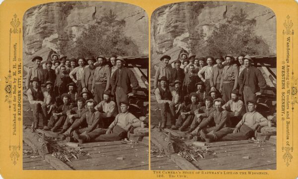 Stereograph of a group of men posing sitting and standing on a raft in front of a rock wall.