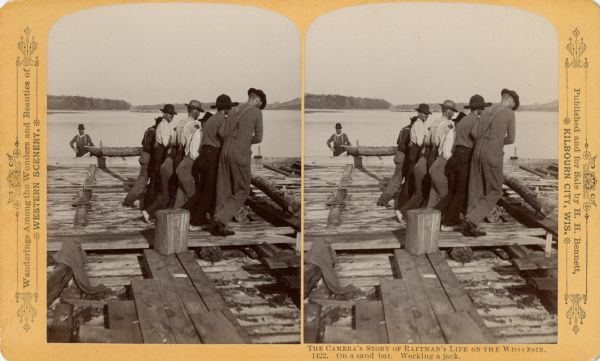 Stereograph of several raftsmen working a jack on a sandbar.