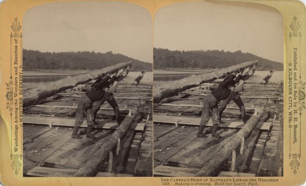 Stereograph of two raftsmen holding a hand-hewn oar above their heads and leaning into it. Another man at the other end of the raft is doing the same.