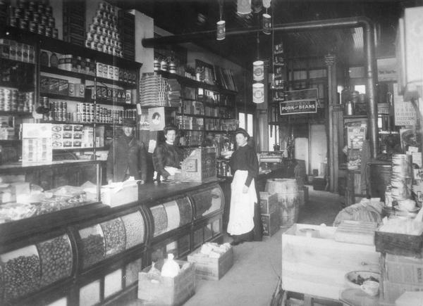 Interior of the Fred Schenk grocery store on the corner of Atwood Avenue and Winnebago Street. Included in the photograph are Art Ramsey, Matilda Schenk, and Elsie Schenk.