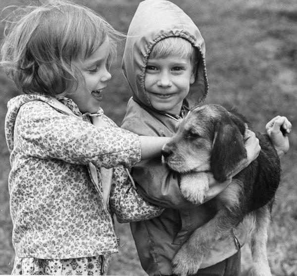 Two children holding a puppy.