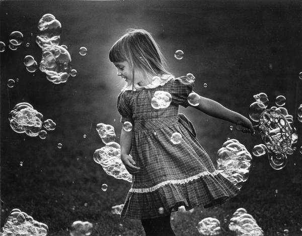 A young girl playing with soap bubbles outdoors.