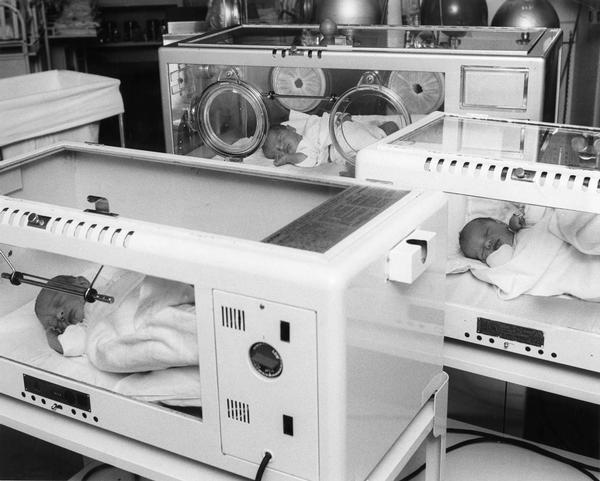 Newborn infants lying in incubators sleeping.