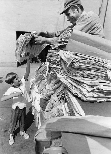 A young Cub Scout member of Pack 86 from Trinity Presbyterian Church hands newspapers he saved to an employee of Shapiro Paper and Metal Co. The task was part of an ecology project that was to gather 2,000 pounds of newspaper in order to save 17 trees.
