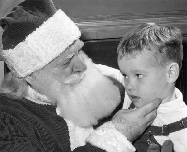 Apprehensive young child on Santa's lap.