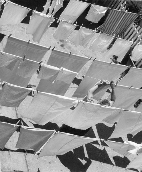 Elevated view of woman hanging up laundry on clotheslines outdoors.