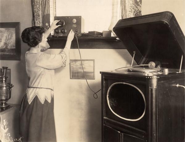 A woman tunes an early crystal radio set.