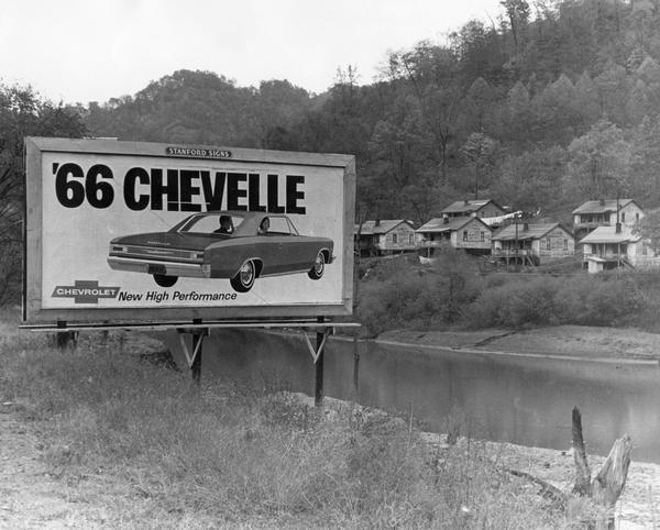 A car advertisement for a 1966 Chevelle on a billboard in a small unidentified Appalachian town.
