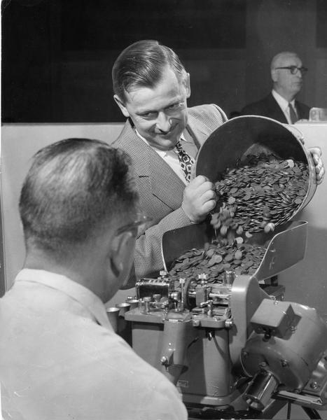 A banker pours 12,320 pennies into a change maker. The man had saved the coins for over four years.