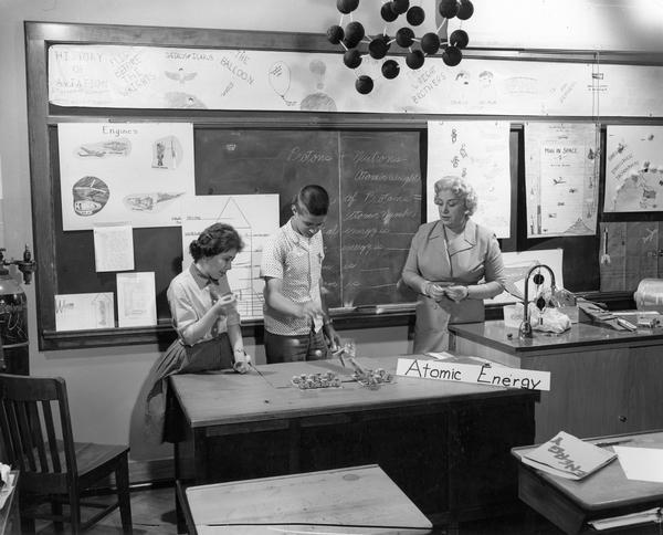 Students and teacher in classroom demonstrating an experiment with atomic energy.