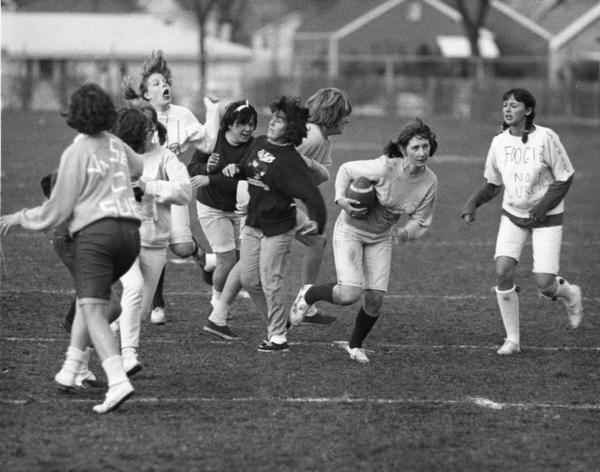 Girls playing football on field.