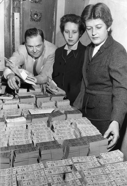 A man and two women with piles of paper tickets being sorted for the upcoming theater season at the Fred Miller theater.