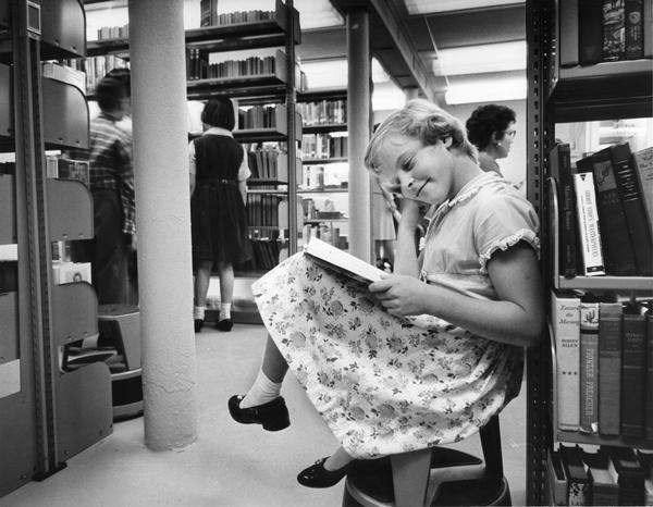 A girl enjoys a book at the library.