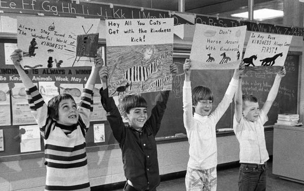 Four children hold up their winning posters for a competition in a class.