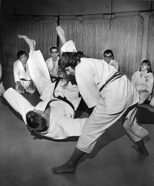 Woman student instructor throwing a male instructor in a class demonstration.