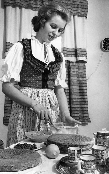 A woman wearing an apron preparing a hazelnut torte from a prized recipe.