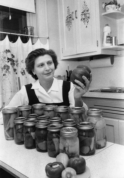 A variety of canned and fresh peppers is artfully displayed by the woman who serves them to her family and gives them as gifts.