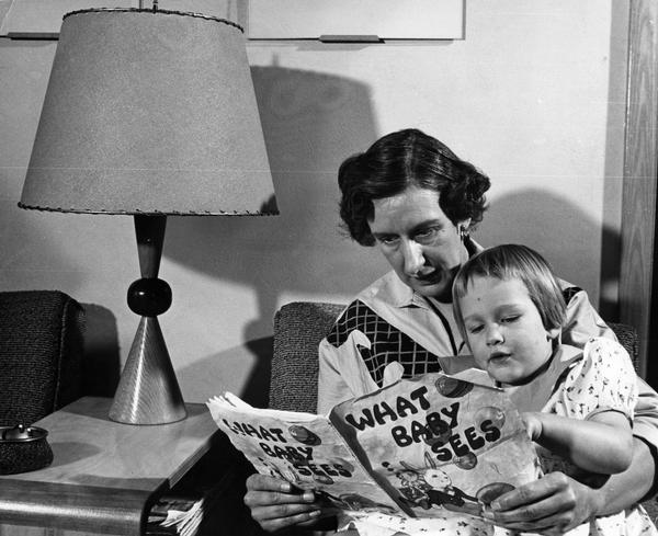 A young child examines a children's book with her grandmother.