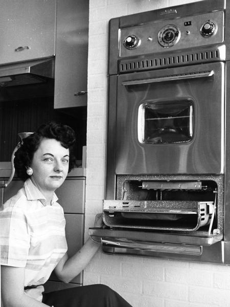 A woman displays an oven.