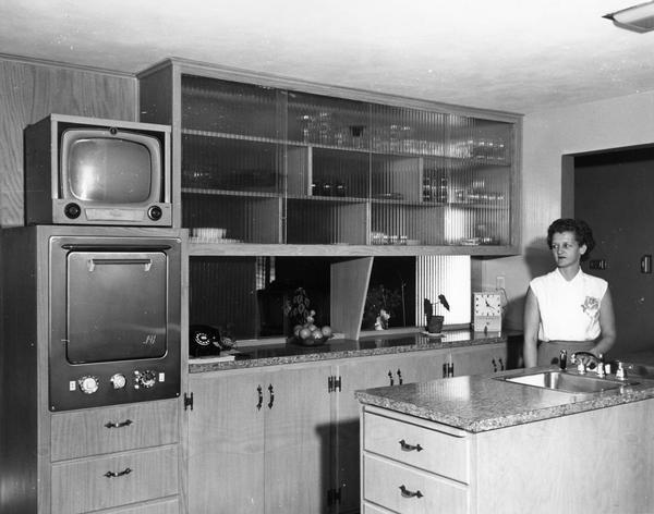 A woman poses her kitchen with all of the modern conveniences.