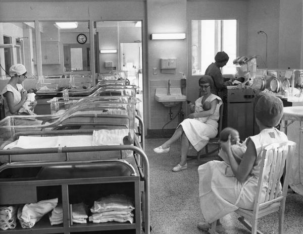 Women feed and rock newborn babies in a neonatal hospital unit.