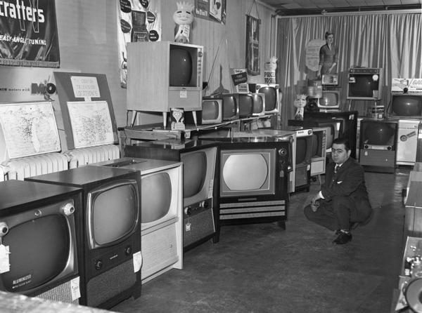 Interior view of the "TV Center" with the proprietor and televisions on display.
