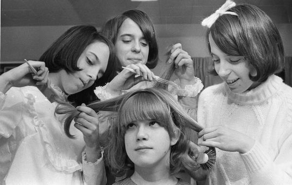 Group portrait of four sisters fixing each others hair.