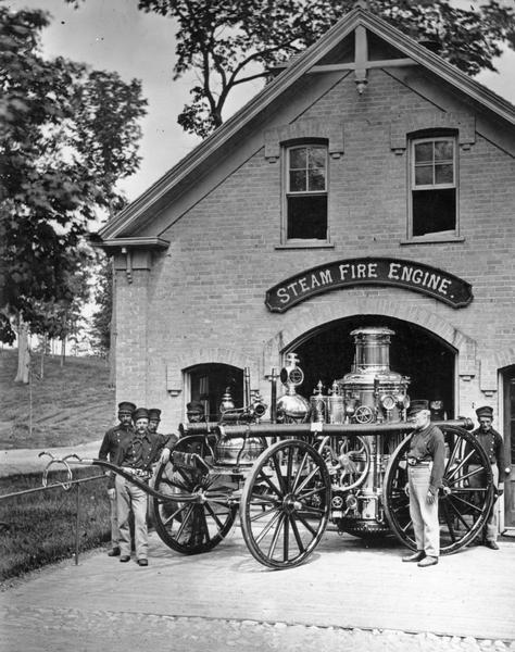 Firefighters stand with steam fire engine in front of fire station at National Soldiers Home.
