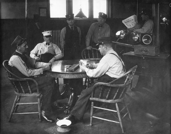 Fireman playing cribbage in a quiet moment at the Dayton and Randall Streets Fire Station Number 4 with spittoon in the foreground.