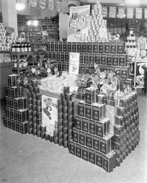 Cans and boxes of Hershey's chocolate products arranged in pyramids on the grocery floor.