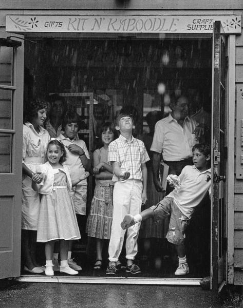 Shoppers take refuge in the open doorway of a shop during a downpour.