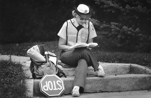 A traffic crossing guard reading while she is waiting for a Grafton elementary school to dismiss its students for the day.