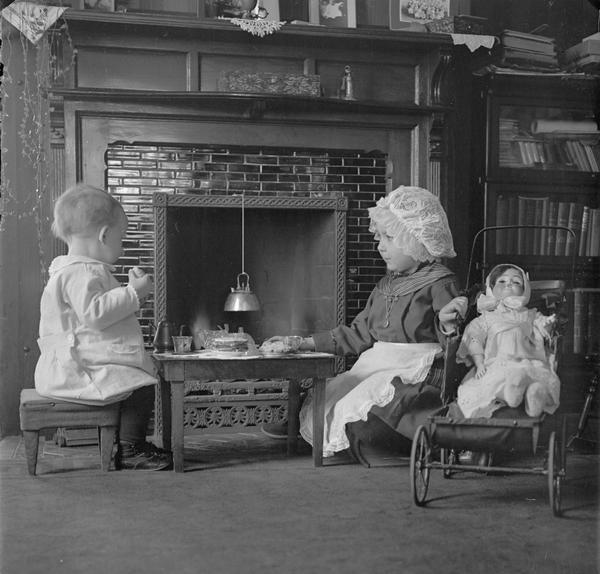 Photographer Herman Taylor's children sit at a little table in front of the hearth in the library.