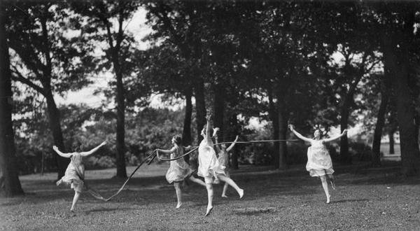 University of Wisconsin physical education interpretive dance students perform out of doors in a grassy meadow.