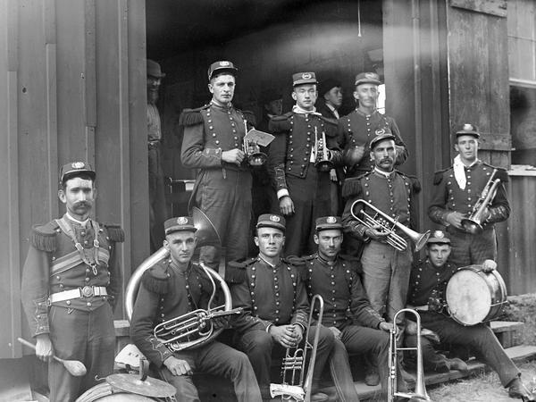 Brass band musicians in uniform pose with their instruments.