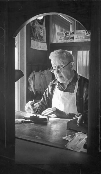 William Behnke goes over bills in his office at the rear of his store, which was in business since July 12, 1899.