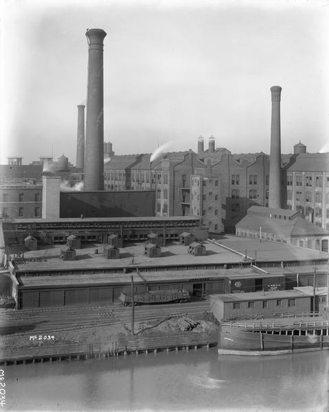 International Harvester's McCormick Works on the river with railroad tracks and a cargo dock. The factory was owned by the McCormick Harvesting Machine Company before 1902.