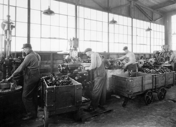 Workers turn out metal parts in a machine shop.
