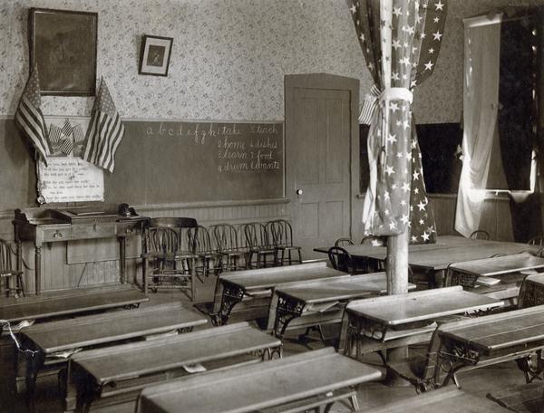 View of an elementary school classroom with two-seater desks. American flags and bunting complete the decor.