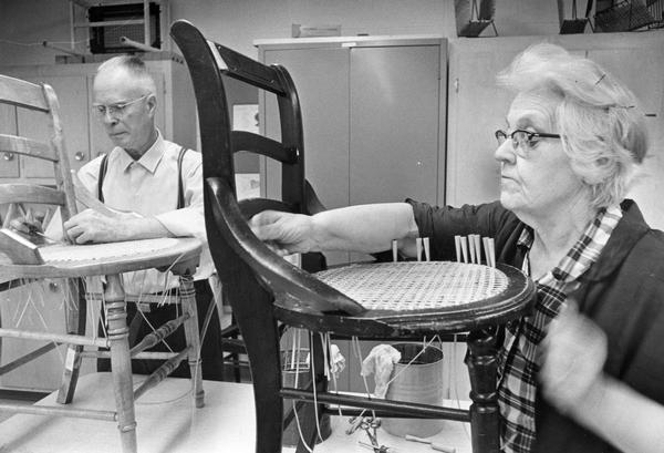 An elderly man and woman make new cane seats for chairs at the Cedar Lake Home for the Aged.