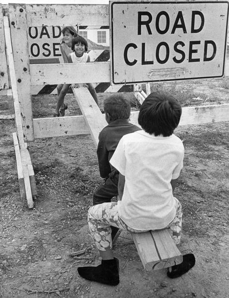 Children fashioned their seesaw using a board, and a barricade with a sign that reads: "Road Closed" that they found in an empty lot.